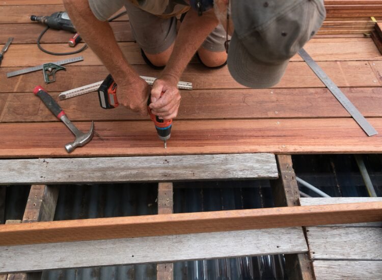 Contractor repairing a wooden deck by Cincinnati Deck Repair.